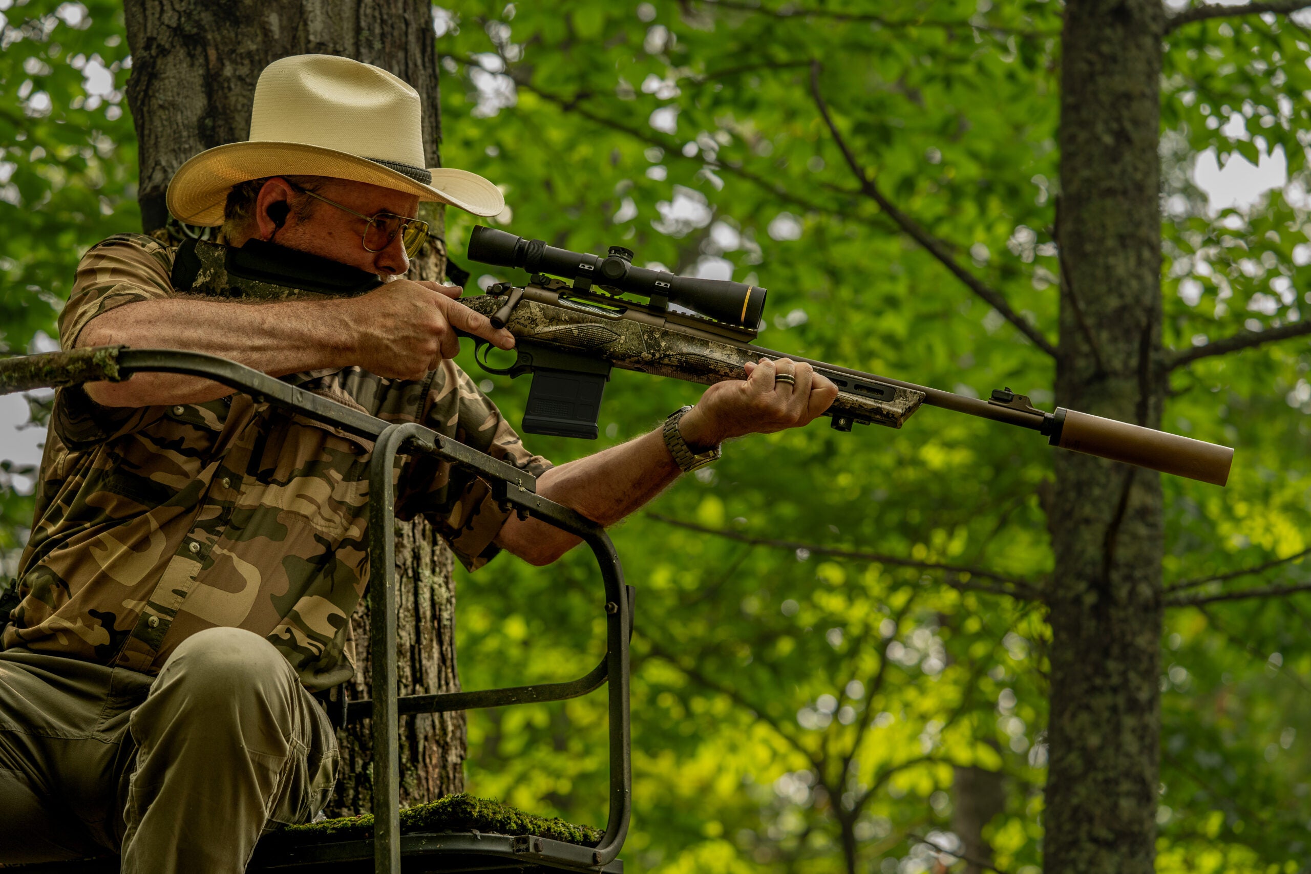 photo of a test-panel member firing a rifle from a ladder-style tree stand