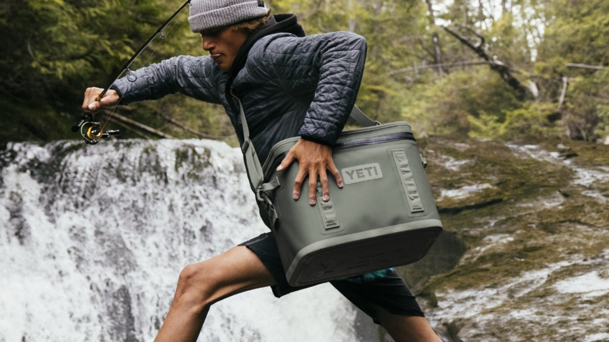 Angler carrying Yeti soft cooler in Camp Green