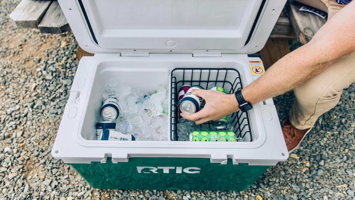 Man filling RTIC hard cooler with ice and drinks