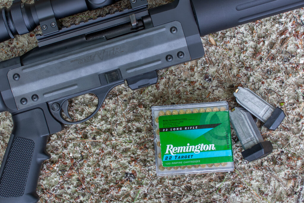 A 22 rifle and Remington 22 LR ammo lying on the ground.