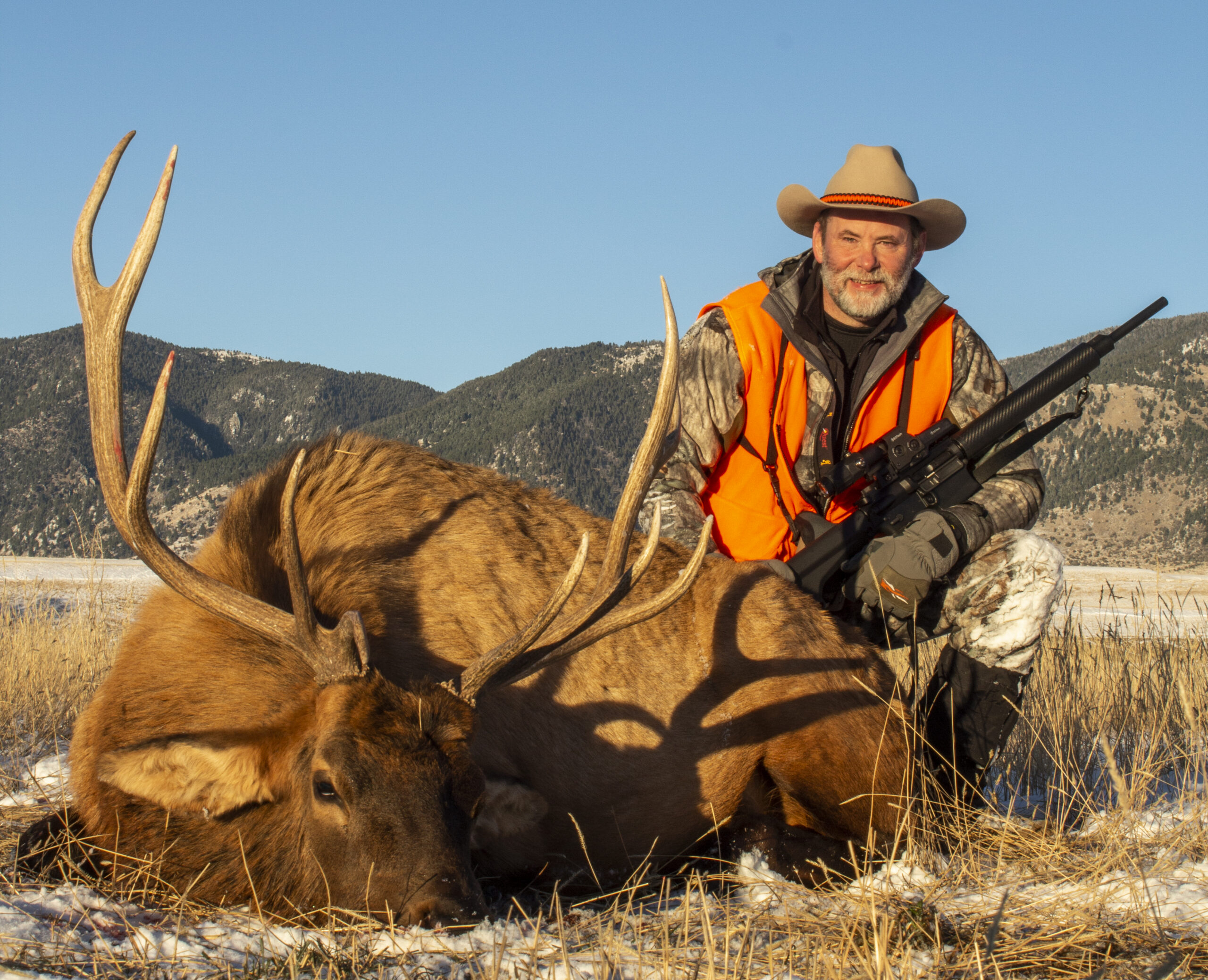 A hunter posing next to a bull elk he harvested.