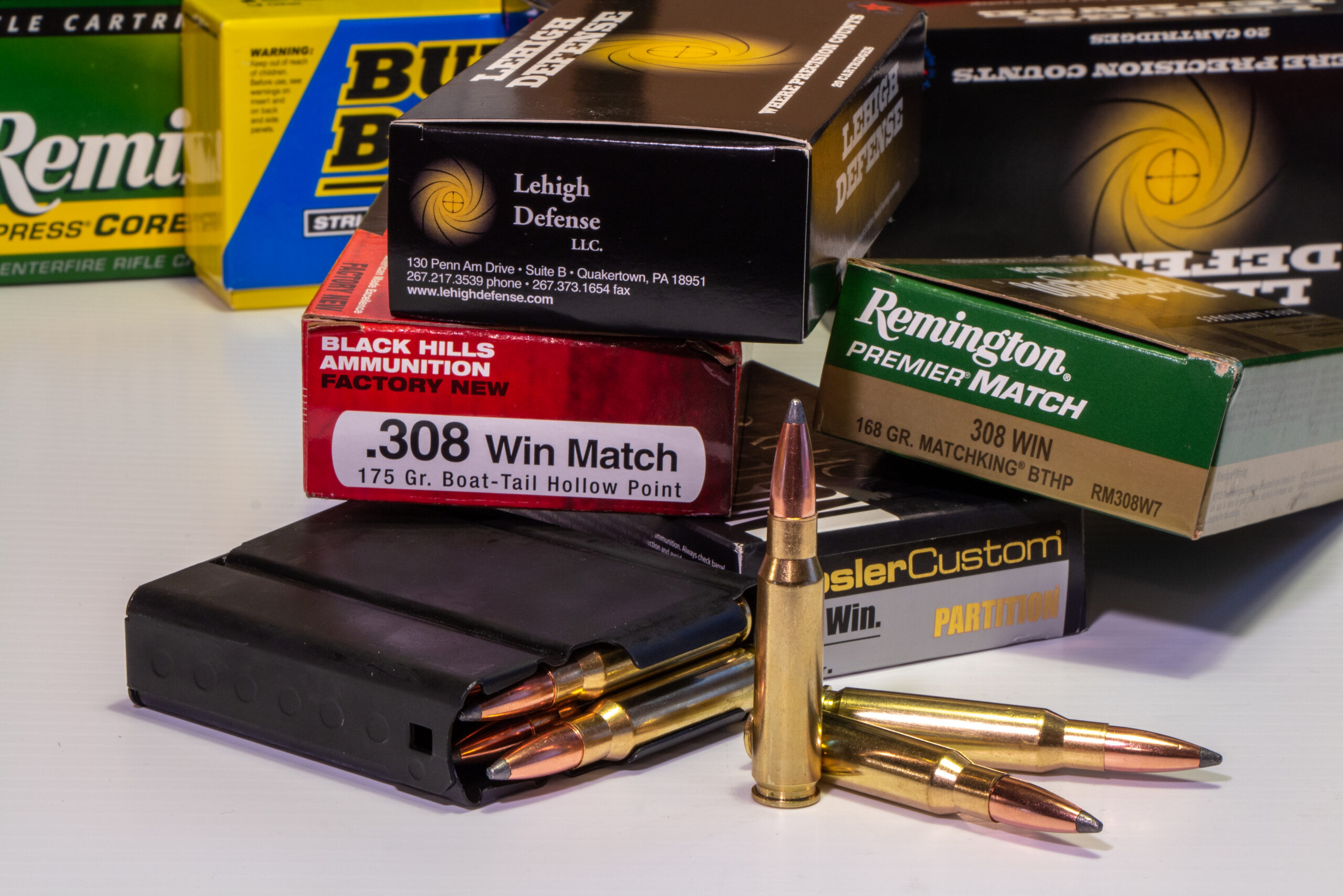 Boxes of 308 Winchester ammo near a rifle magazine loaded with cartridges.
