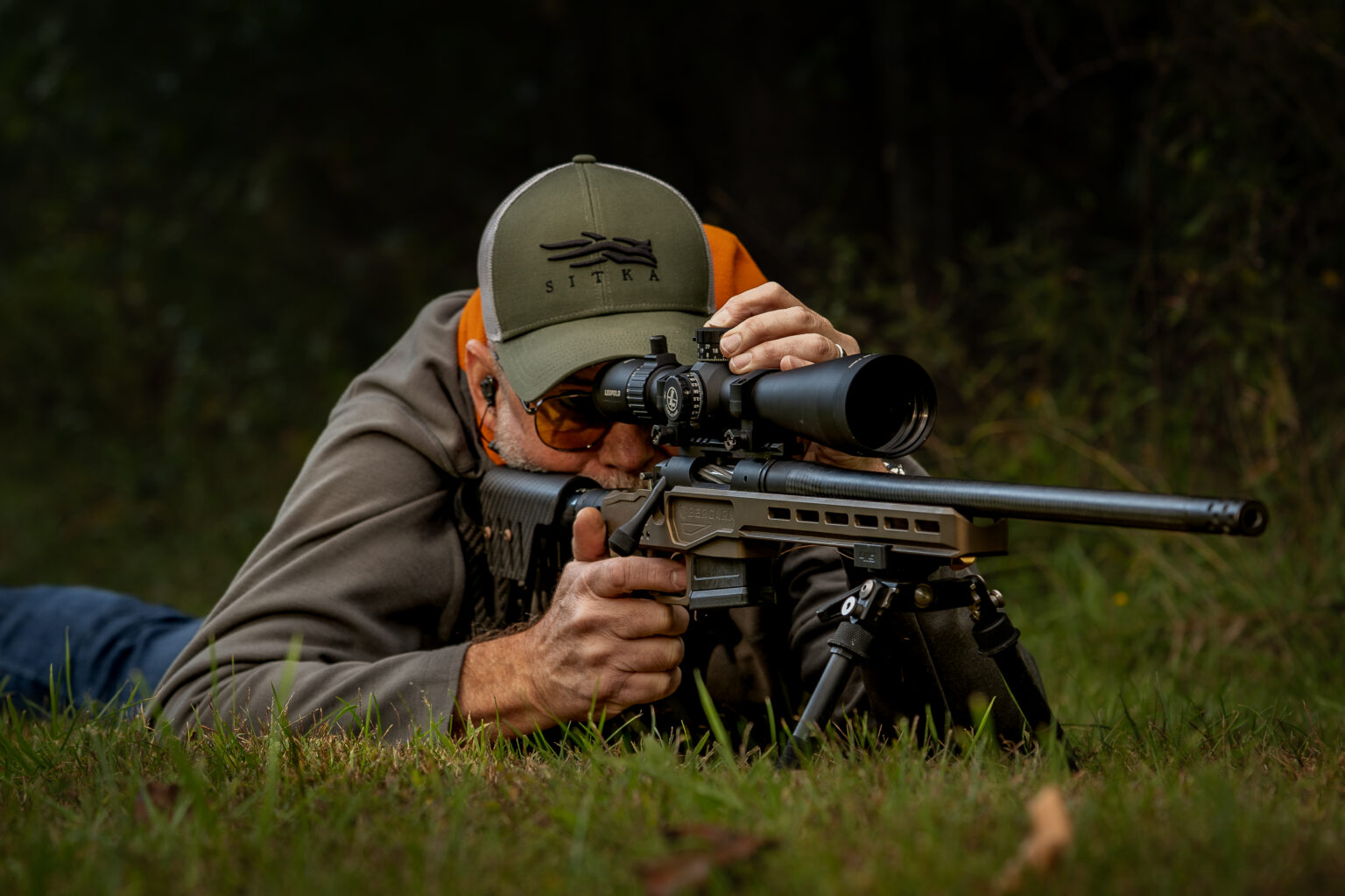 A man shoots a precision rifle from the prone position.