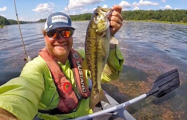 An angler holds a spotted bass. 