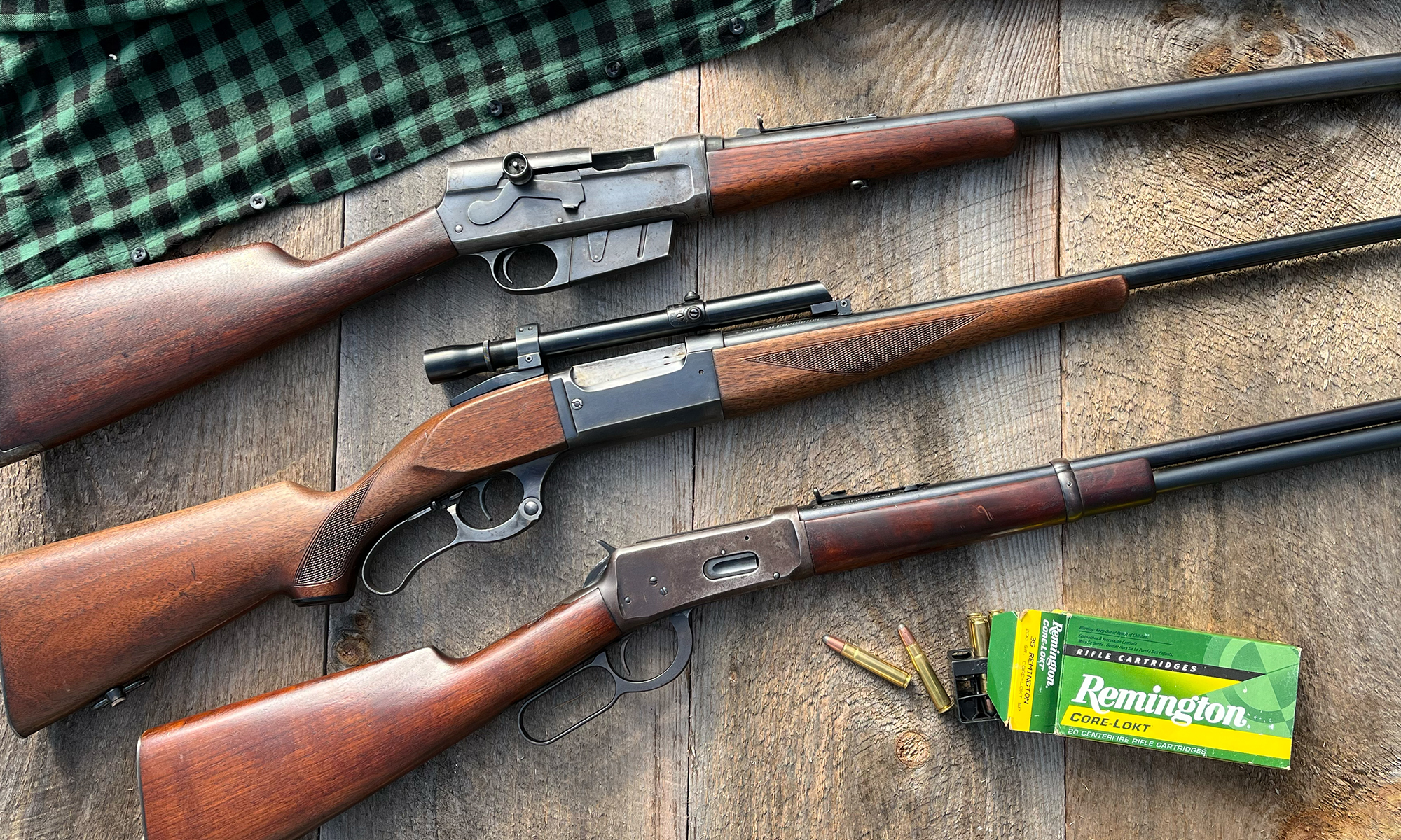 Three classic deer rifles on a wood background.