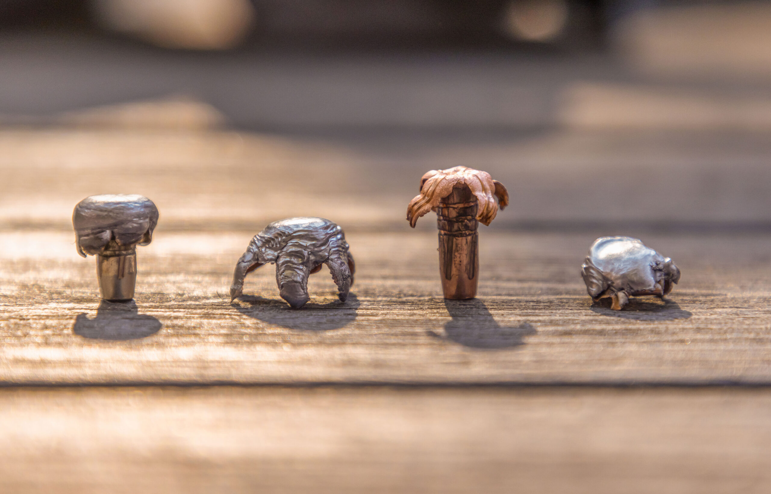 Four spent rifle cartridges displayed on a bench. 
