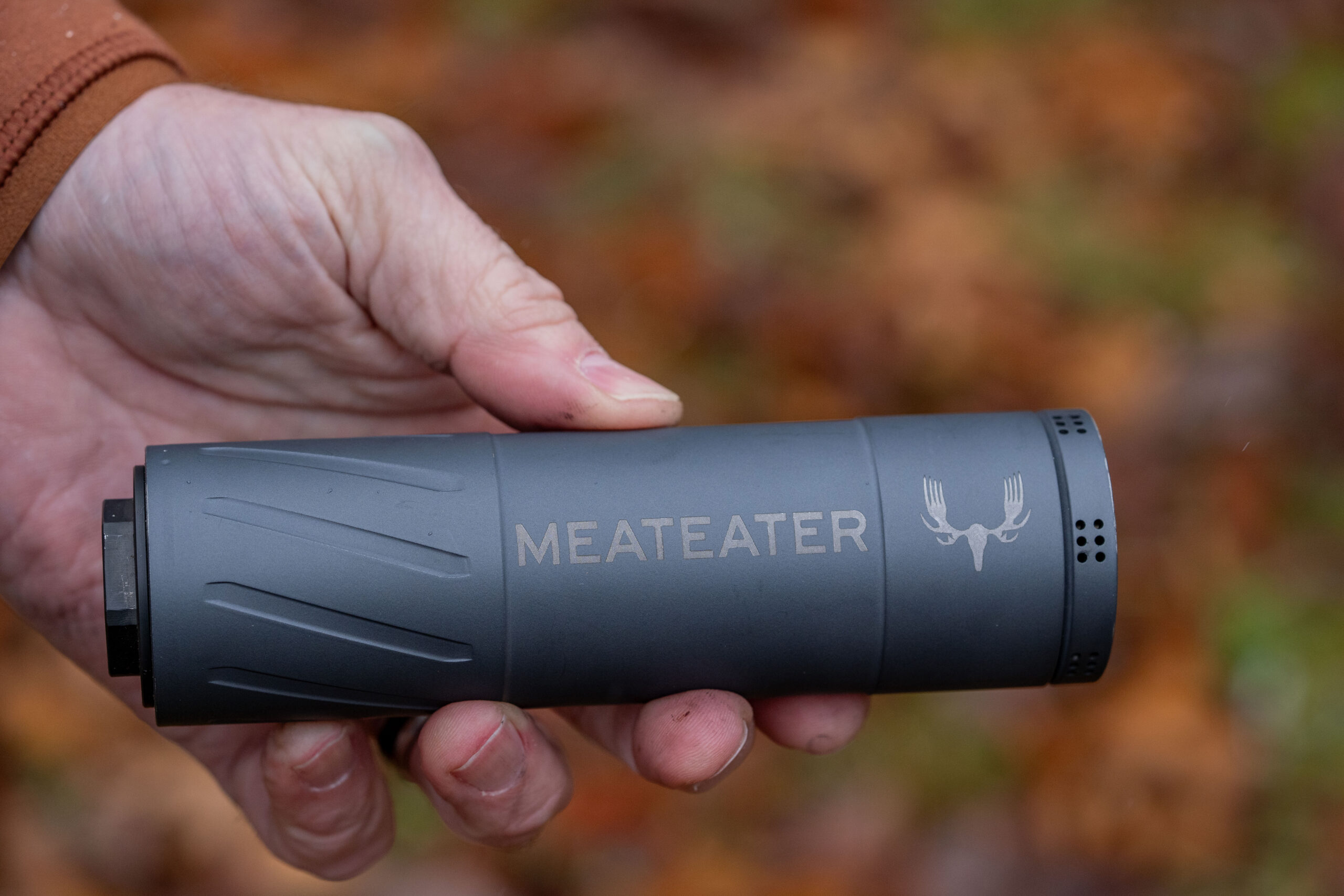 A shooter holds a rifle supressor. 