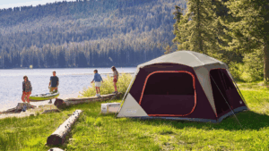 Coleman tent pitched beside a mountain lake with family enjoying outdoor camping