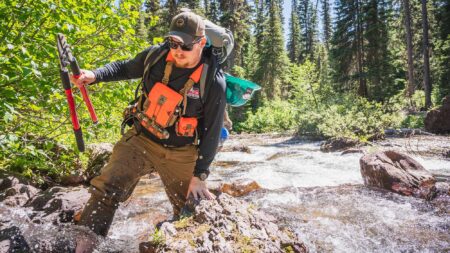 A Wild Mission: Getting Our Military Veterans Outdoors Hiker crossing rocky mountain stream with loppers and large backpack in forest