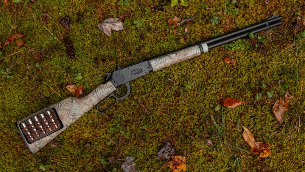 A custom Winchester Model 94 lying on the grass.