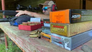 Which .300 Blackout Ammo Should You Buy? We Tested the Top Loads Shooter at gun range testing multiple 300 Blackout ammunition brands on wooden bench