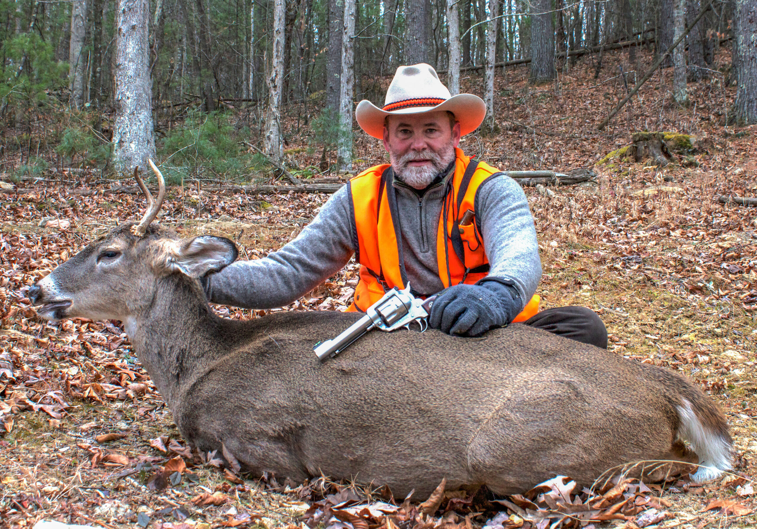 A hunter poses with a whitetail deer taken with a handgun. 