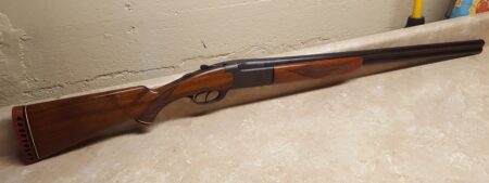 Over-under double barrel shotgun with walnut stock lying on floor