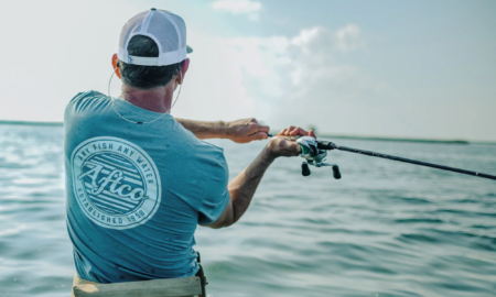 Man wearing Aftco fishing shirt casting rod over open ocean water