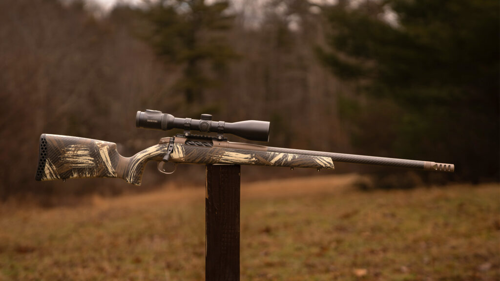 Weatherby Alpine rifle balanced on a post in a field. 