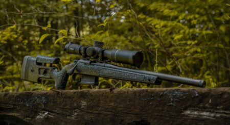 Bergara B-14R Carbon Rifle: Tested and Reviewed Bolt-action sniper rifle with Leupold scope resting on a log in forest