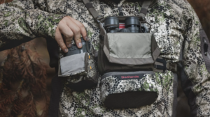Hunter in camo gear using Badlands chest pack with binoculars and rangefinder