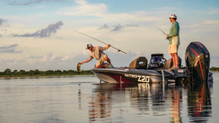 Two anglers fishing from a Nitro Z20 bass boat on calm water.