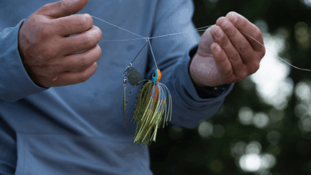 Person holding colorful fishing lure with skirt and spinner blade on fishing line