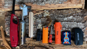 Collection of fire starters including BIC, Zippo, SOL, and Frog Co lighters on wood.