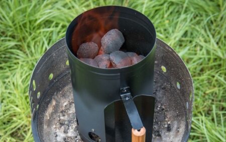 The 5 Best Charcoal Chimneys of 2024 Charcoal chimney starter with lit briquettes glowing red on outdoor grill base