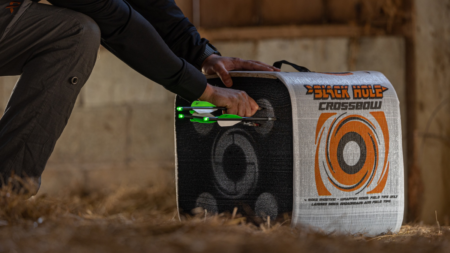 The 6 Best Crossbow Targets of 2024 Person retrieving green arrows from Black Hole Crossbow archery target bag outdoors.