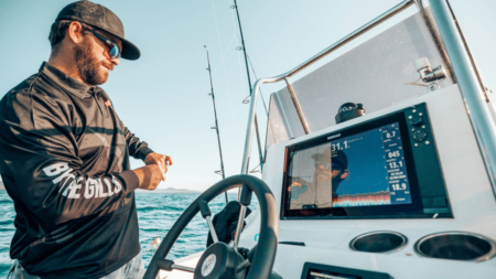 The Best Boat Accessories of 2024 Man operating fishing boat with Simrad GPS chartplotter display on open ocean waters.