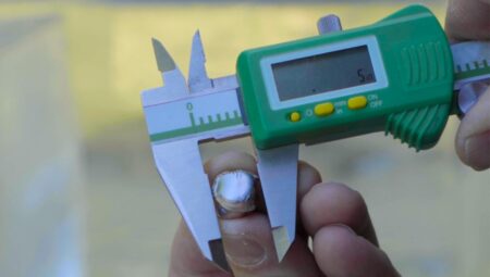 Digital caliper measuring small metal object displaying 5mm reading on LCD screen