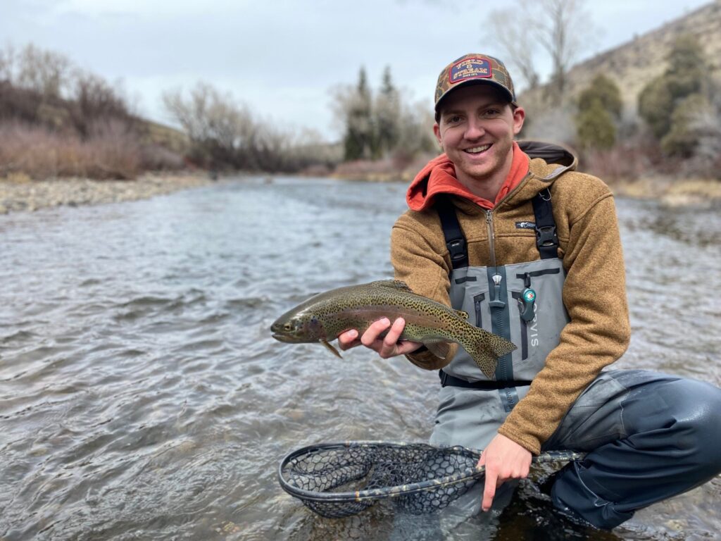 Angler holding fish in river wearing Orvis waders