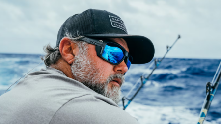 Costa Fishing Sunglasses Are Up to $70 Off at Prime Day Bearded fisherman wearing blue mirrored sunglasses and captain hat on deep sea fishing boat