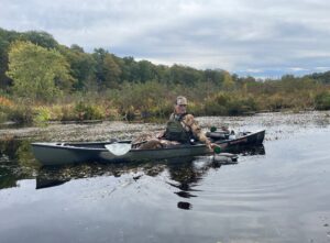 We’ve Hunted From a Lot of Kayaks—These Are Our Favorites Hunter in camouflage paddling Old Town kayak with duck decoys on calm river.