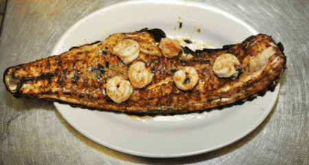 Recipe: Woodland’s Redfish on the Half Shell Grilled blackened fish fillet topped with seasoned shrimp on white oval plate