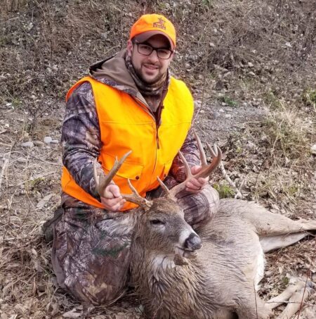 Why 20-Gauge Slugs Are Better Than 12-Gauge Slugs Hunter in blaze orange posing with harvested whitetail buck deer outdoors.