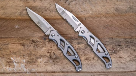 Two open Gerber folding pocket knives displayed on a wooden surface.