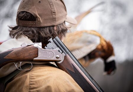 Types of Shotguns: A Complete Guide Hunter carrying over-under shotgun with harvested pheasant in background