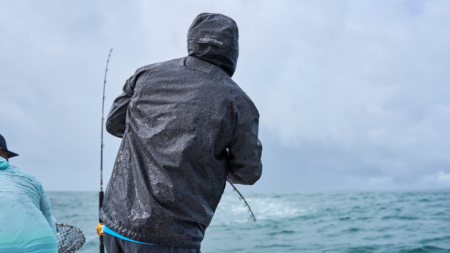 The Best Rain Gear for Fishing, According to Our Tests Two anglers fishing in heavy rain wearing Grundéns waterproof jacket on choppy ocean waters.