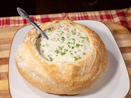 How to Cook Lake Trout Chowder Creamy clam chowder soup served in a sourdough bread bowl garnished with chives.