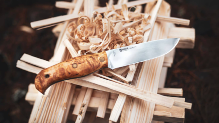 Helle Norway fixed blade knife with curly birch handle resting on wooden shavings