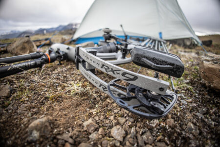 Hoyt Carbon RX-9 compound bow resting on rocky ground near camping tent outdoors