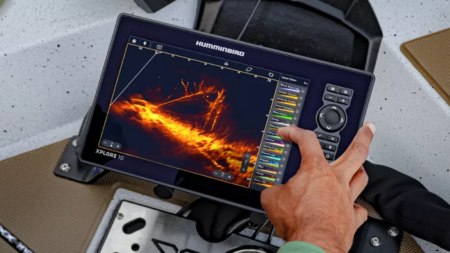 Humminbird Xplore 10 fish finder displaying sonar image on boat with hand touching screen