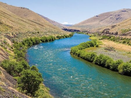 Turquoise river winding through arid canyon valley with green riparian vegetation