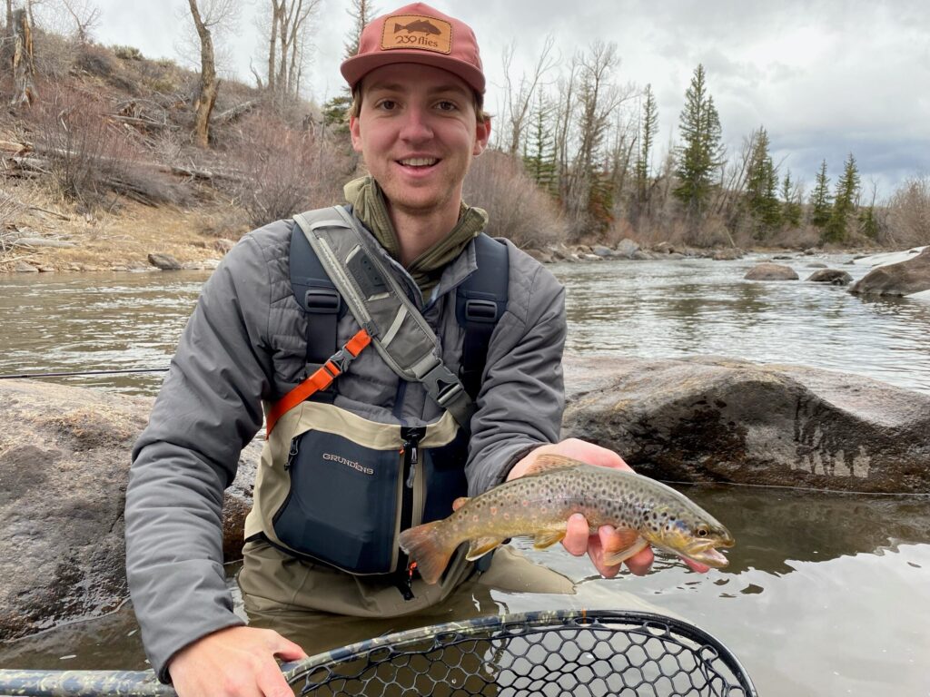 Fly fisherman holding fish wearing Grundens waders