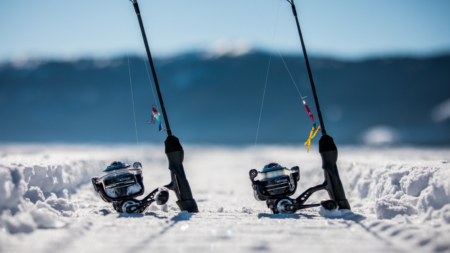 Best Ice Fishing Lures for Perch in 2025 Two ice fishing rods with colorful lures resting in snow on frozen lake.
