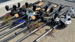 Multiple fishing rods with baitcasting reels and jig lures laid on boat deck.