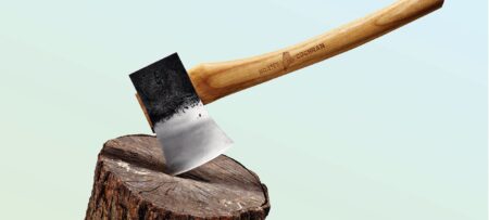 The Best Gear for Hunting Camp Brant Cochran axe with wooden handle embedded in a tree stump