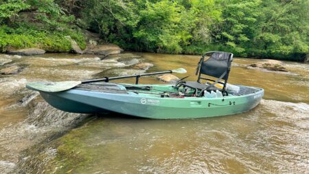 Magellan Outdoors Angler Fishing Kayak, Expert Tested Green Magellan fishing kayak with paddle and seat on rocky river