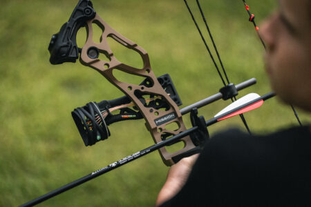 Person aiming a Mission compound bow with arrow nocked outdoors