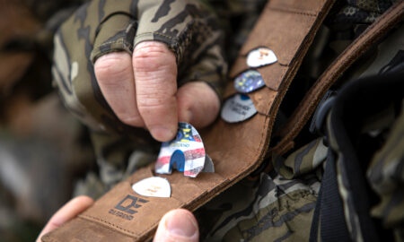 How to Use a Turkey Mouth Call Like a Pro Person in camouflage gloves holding guitar picks from a leather DEFEND wallet