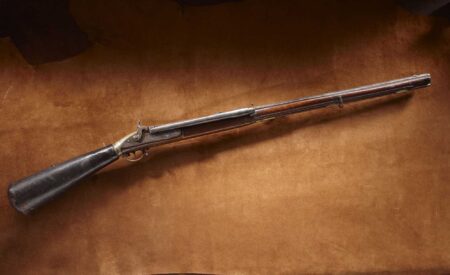 How to Buy an Air Gun Antique flintlock musket with wooden stock displayed on brown velvet surface