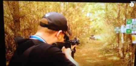 Person aiming rifle at targets on outdoor woodland shooting range